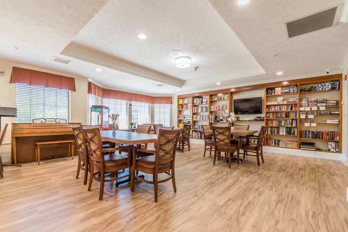 Spacious library with wooden floors, filled with tables, chairs, and bookshelves.