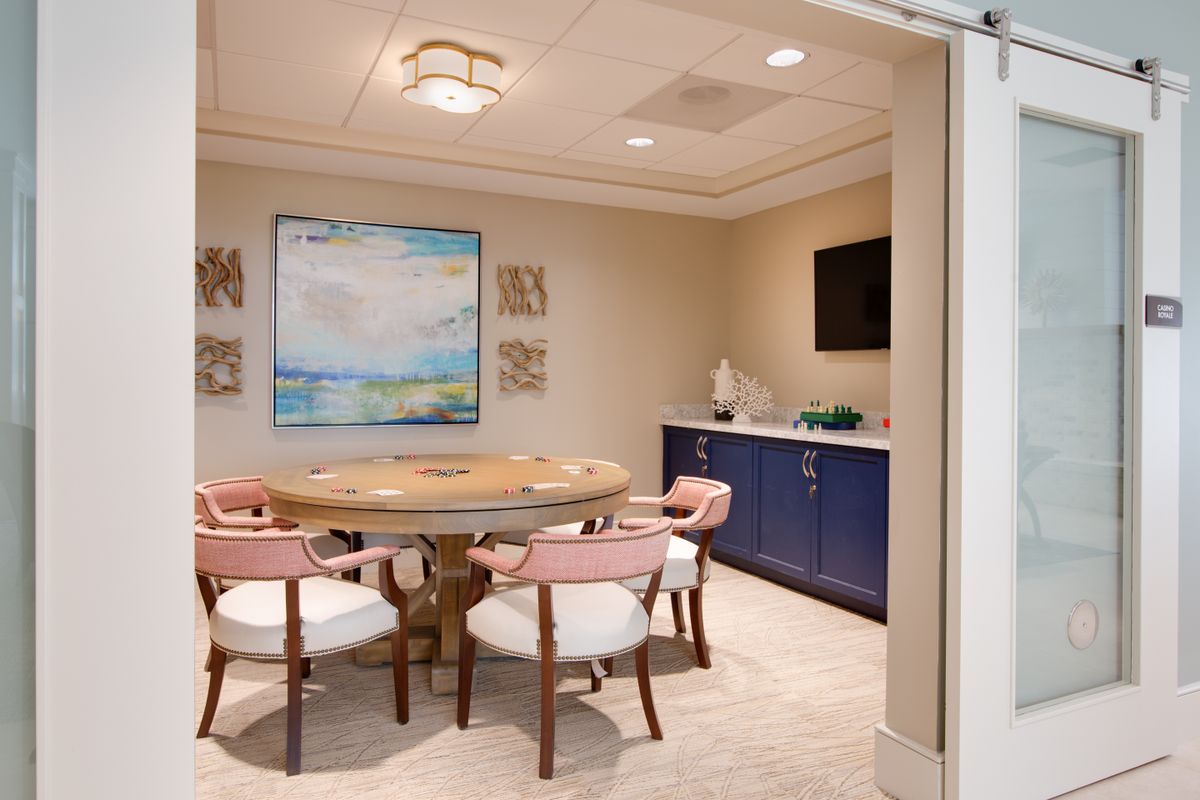 A modern meeting room with a round table and stylish chairs, featuring artwork and a mounted television.