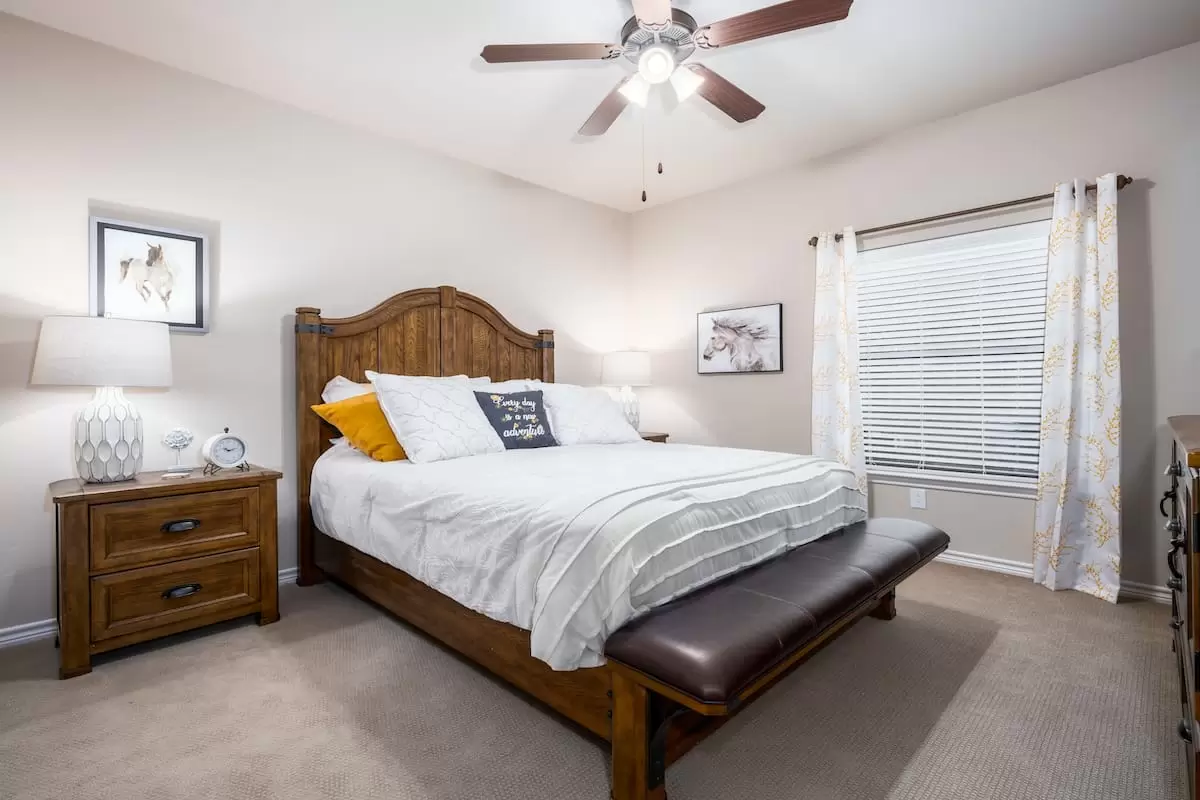 Cozy bedroom interior with a large bed, ceiling fan, and soft lighting.