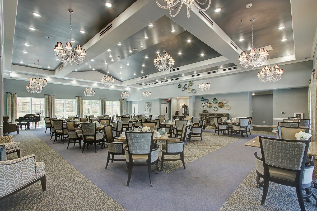 A spacious and elegantly decorated dining area with chandeliers and stylish furniture.