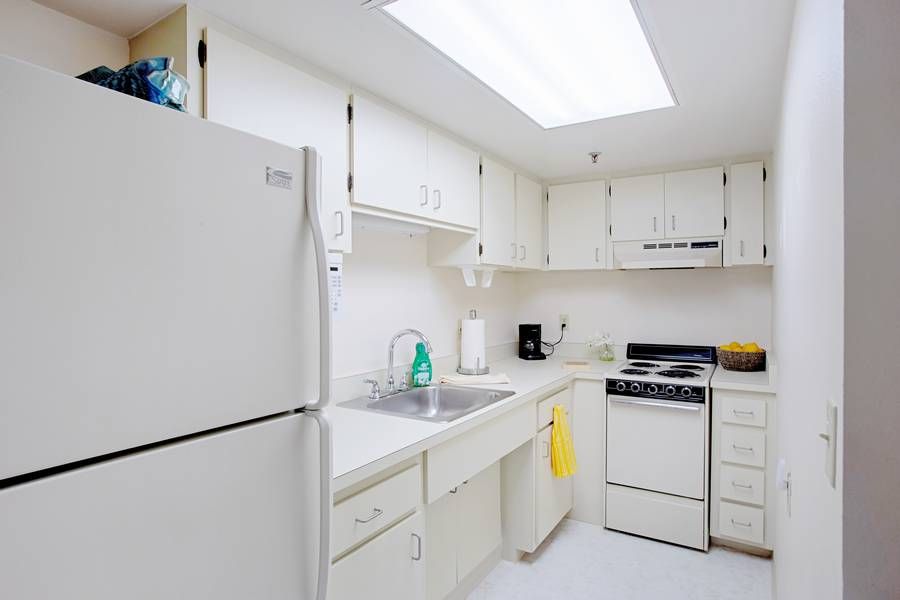 A small, bright kitchen with white cabinets and appliances.