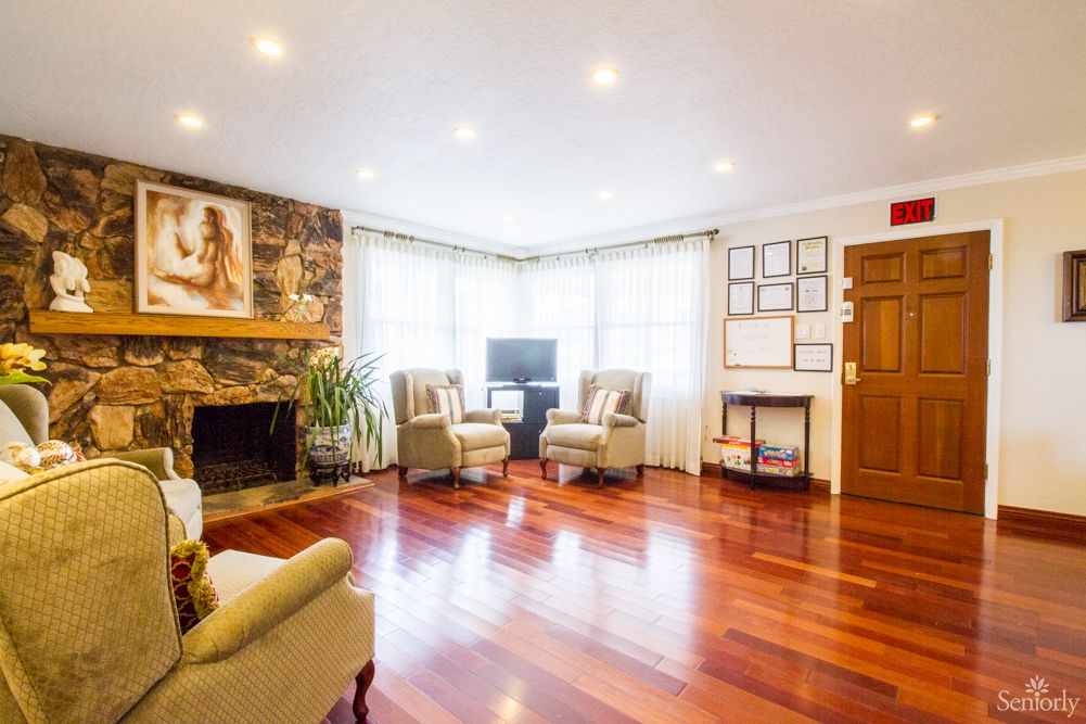 A cozy living room with hardwood flooring, featuring a fireplace and comfortable seating.