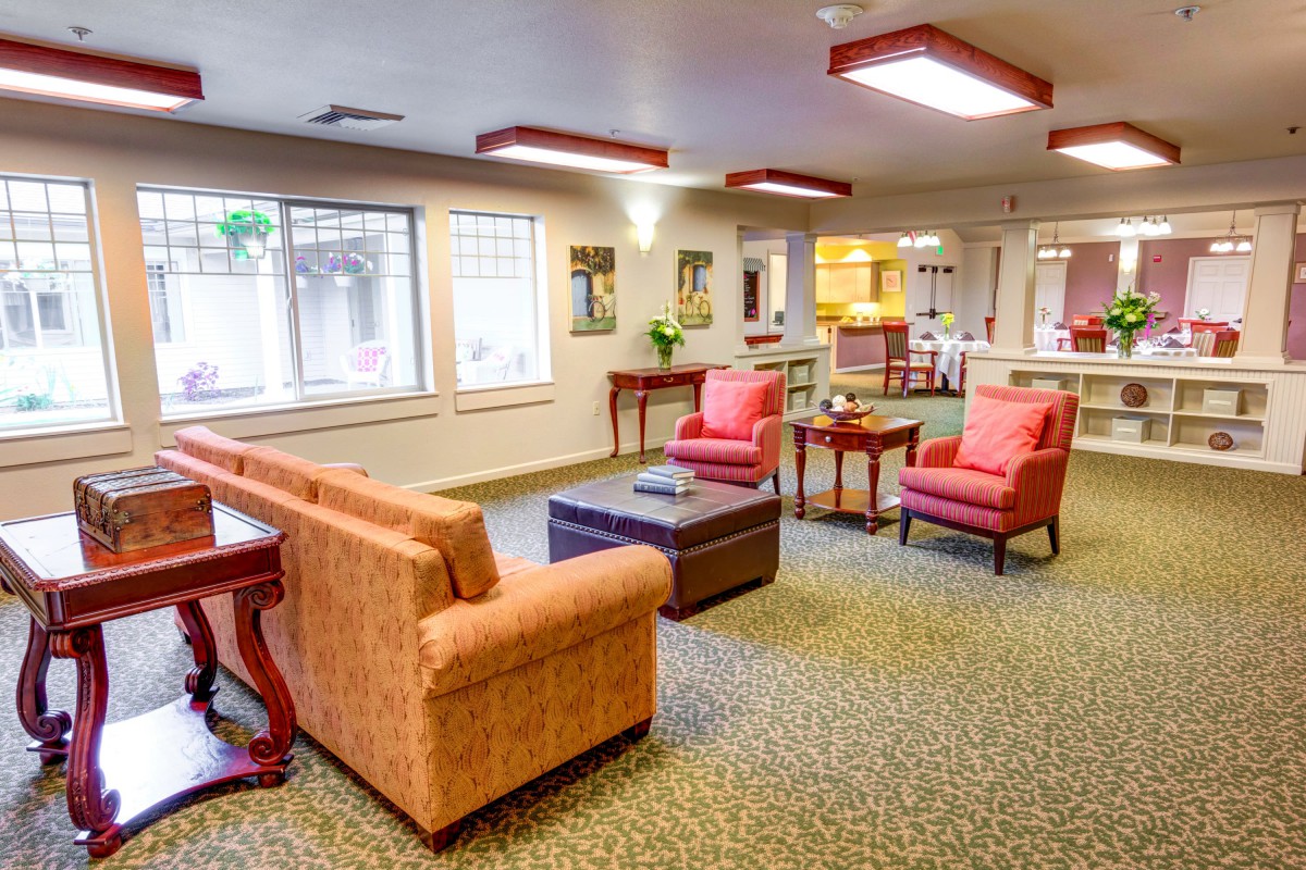 A cozy living room area with sofas, chairs, and a coffee table arranged on a carpeted floor.
