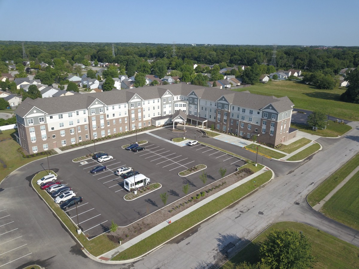 Aerial view of a residential building with a parking lot in a suburban area.