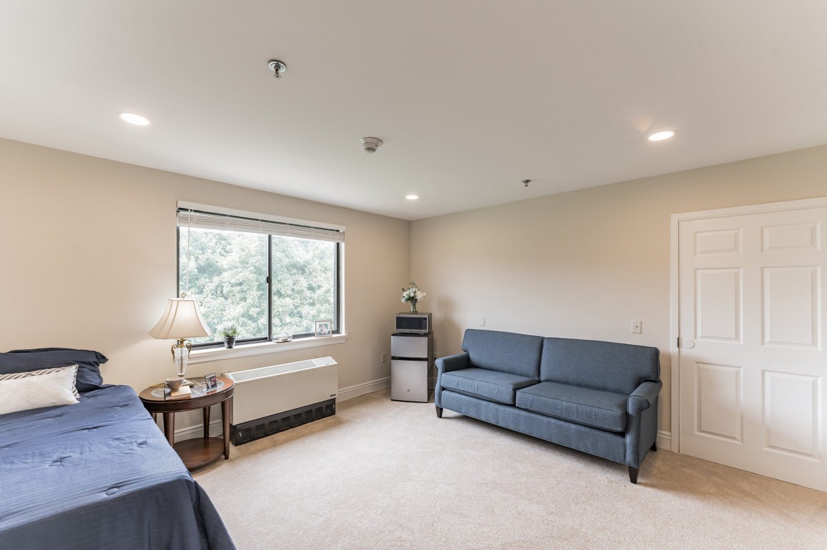 A cozy minimalist living room with a blue sofa, lamp, and large window.