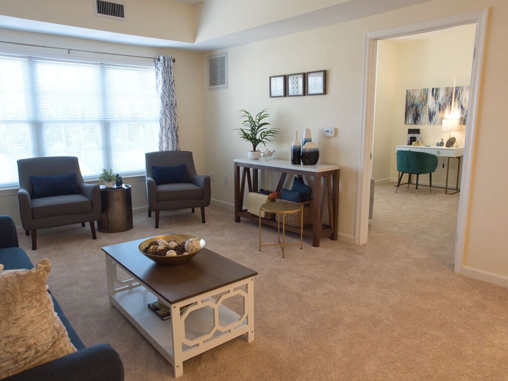 A cozy and well-decorated living room with comfortable chairs, a coffee table, and wall art.