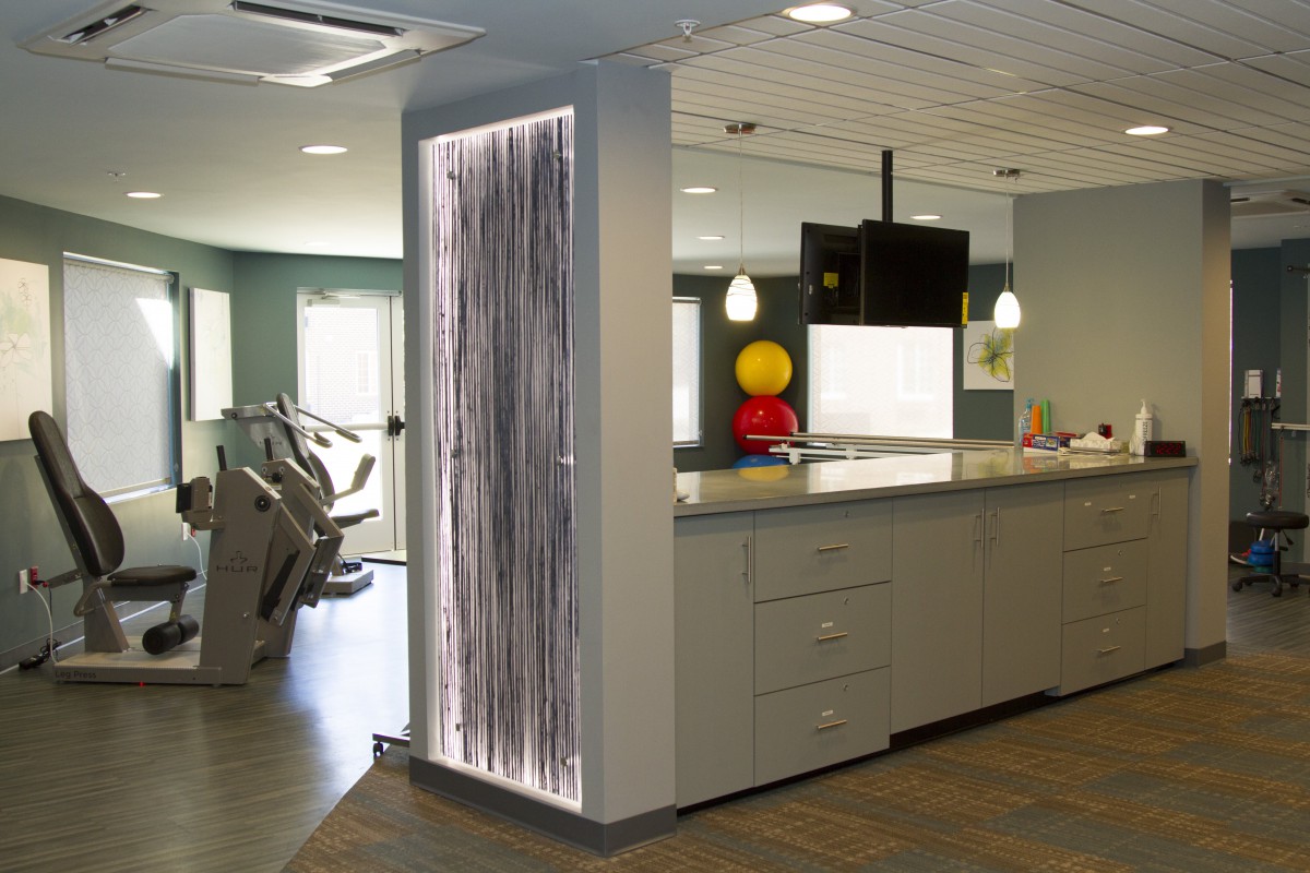 A modern, open-concept kitchen area with contemporary lighting and adjacent exercise equipment.