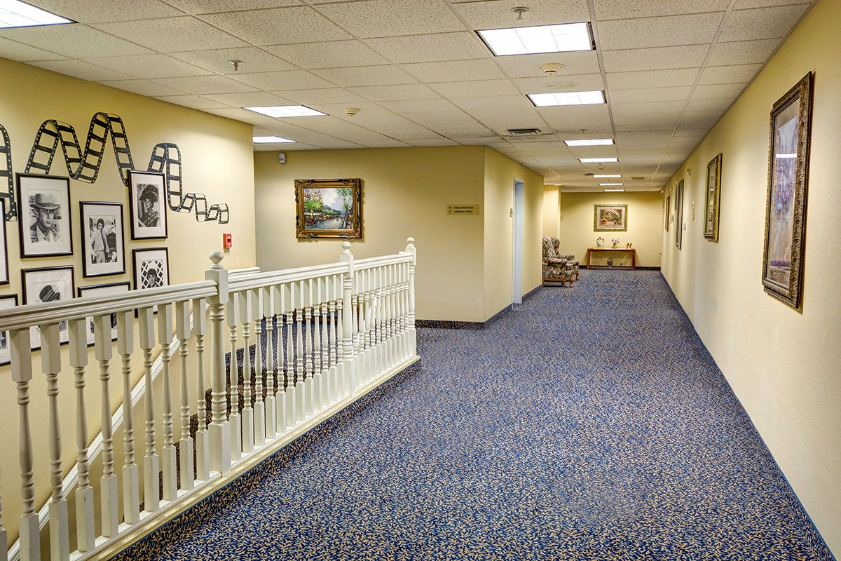 A well-lit hallway with carpeted floors and framed artwork on the walls.