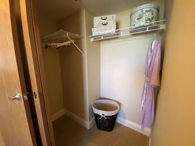 A neatly organized closet with clothes hangers, a laundry basket, and shelves storing various items.