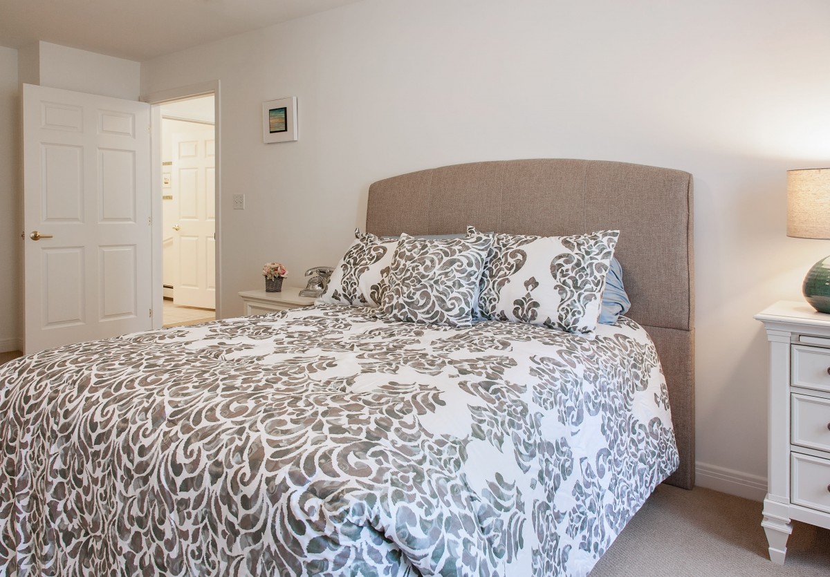 A cozy and modern bedroom featuring a bed with patterned bedding and neutral decor.