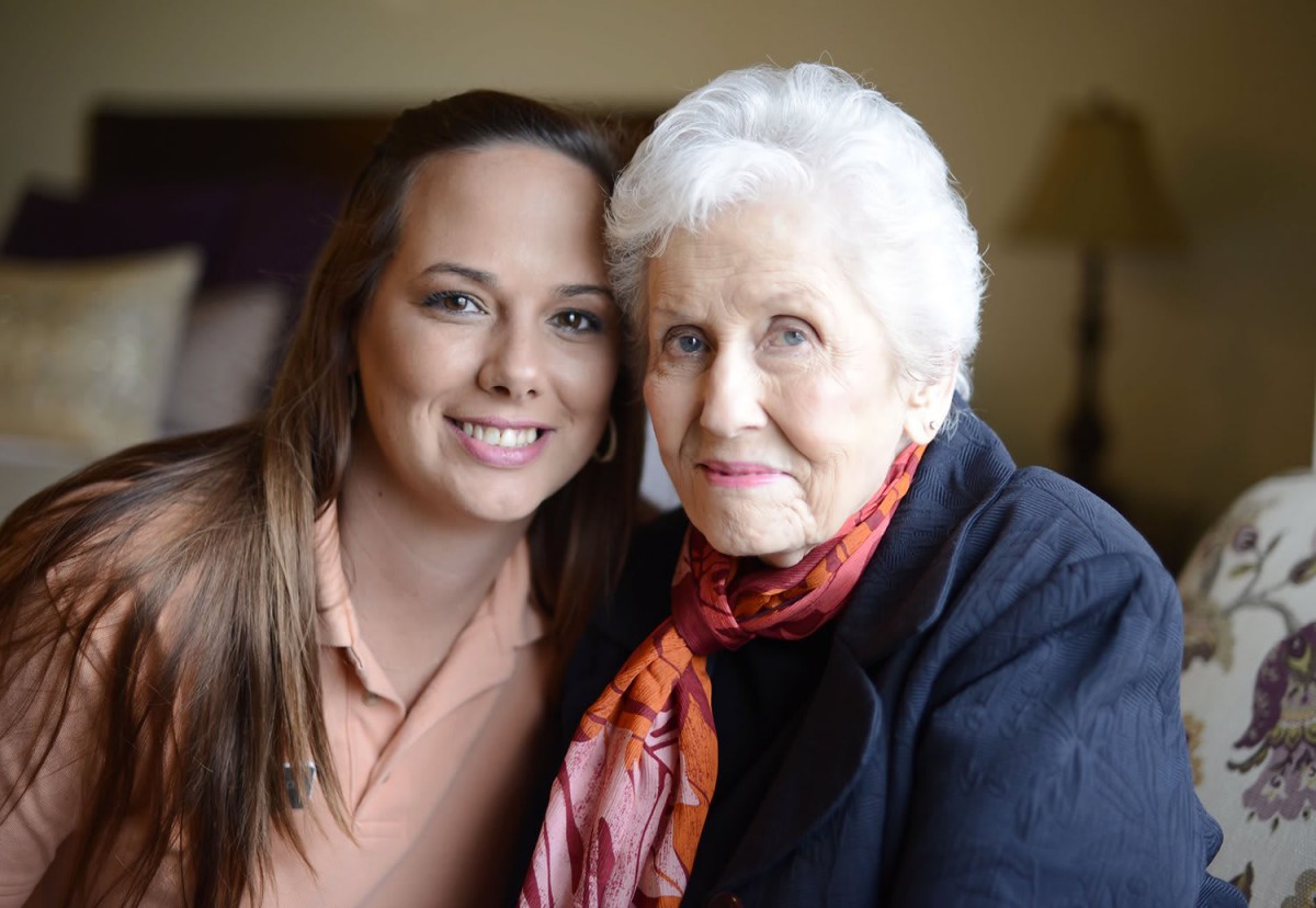 A young woman sitting closely with an elderly woman, showing a warm family bond.