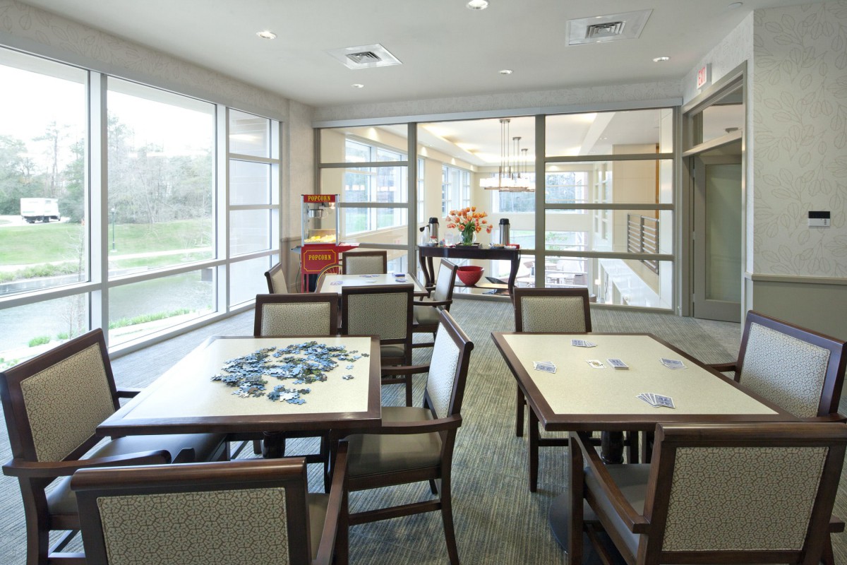 A modern dining area with tables and chairs, featuring large windows for natural light.