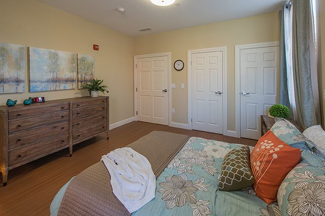 A cozy bedroom with a neatly made bed, dresser, and wall decor.