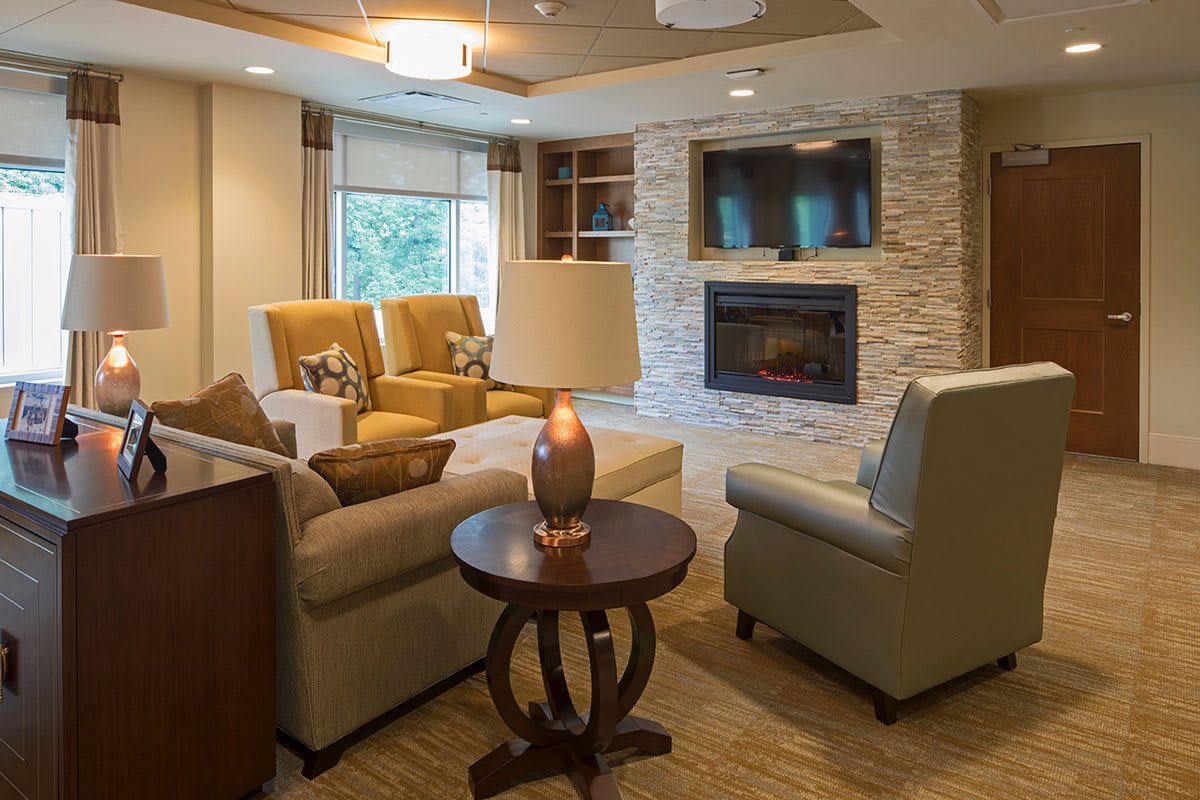 A cozy and modern living room with comfortable seating around a stone fireplace.