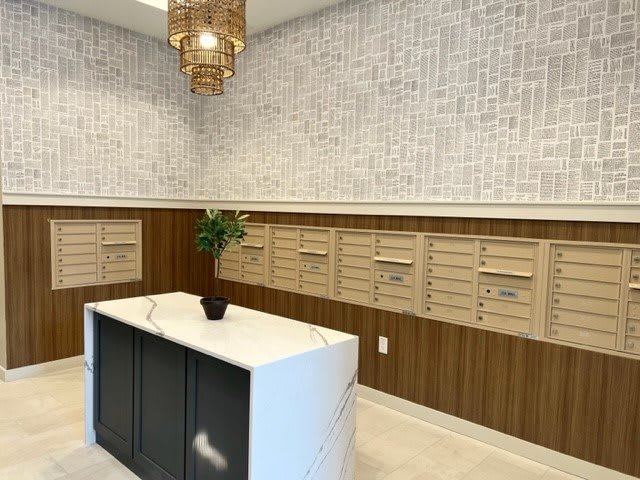 A modern mail room with a row of mailboxes, a central counter, and elegant decor.