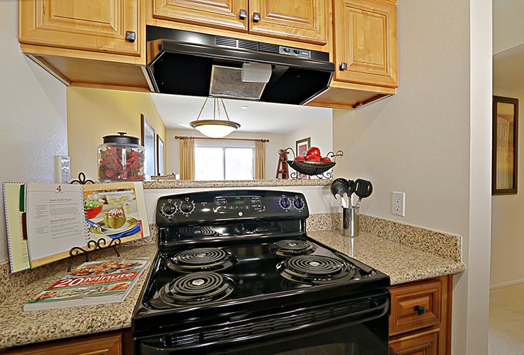 A modern kitchen with a black stove and wooden cabinets.