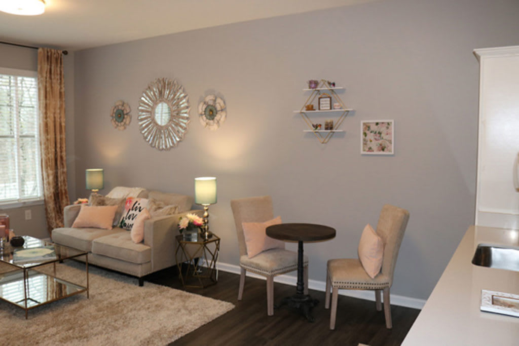 A cozy living room with modern decor, featuring a sofa, small dining table with chairs, and stylish wall decorations.