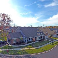 A suburban neighborhood with neatly lined houses and well-maintained lawns under a clear blue sky.