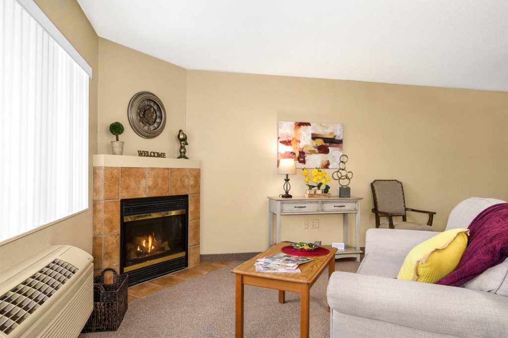 A cozy living room with a fireplace, sofa, and decor items, creating a warm and inviting atmosphere.