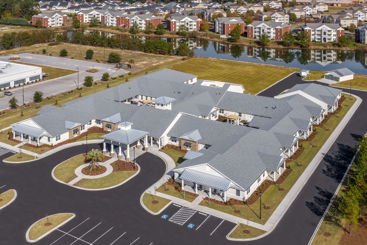 An aerial view of a large building complex with a parking lot in a suburban area.