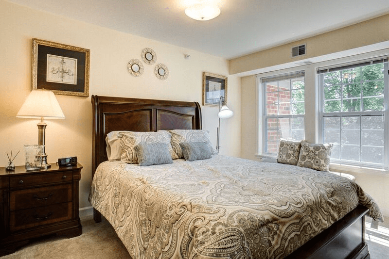 A cozy bedroom with a large bed, wooden headboard, and decorative pillows by the window.