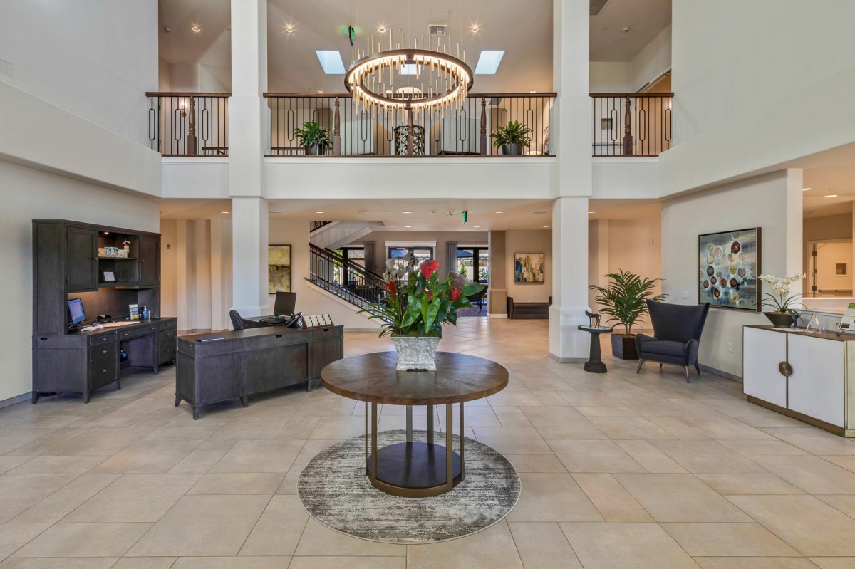 A modern lobby with a central table, chandelier, and elegant furnishings.
