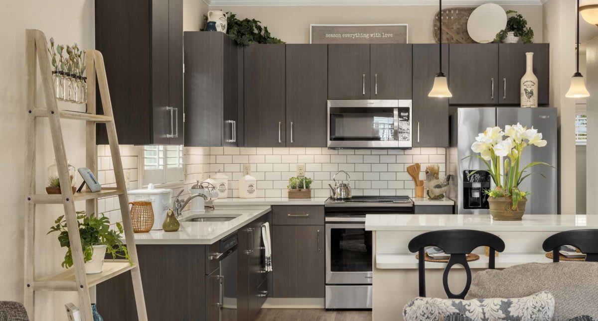 A modern kitchen with dark cabinets, stainless steel appliances, and a white subway tile backsplash.
