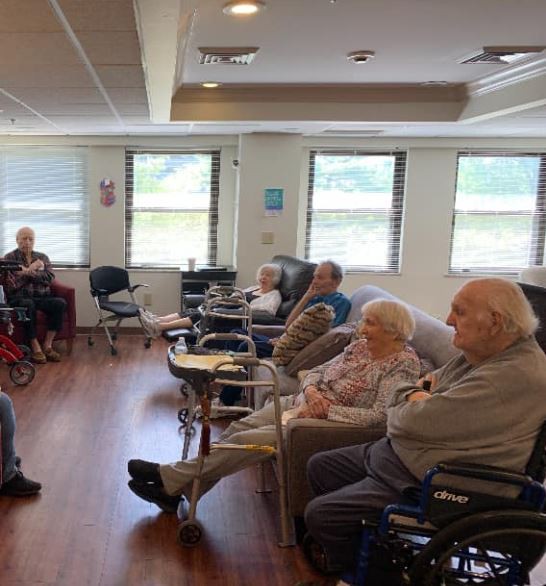 A group of elderly individuals seated in wheelchairs inside a nursing home.