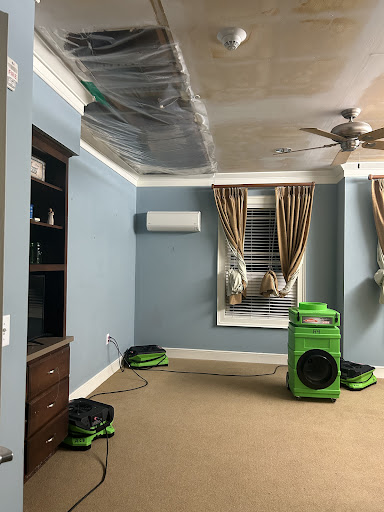 A living room undergoing renovation with drying equipment and covered ceiling.