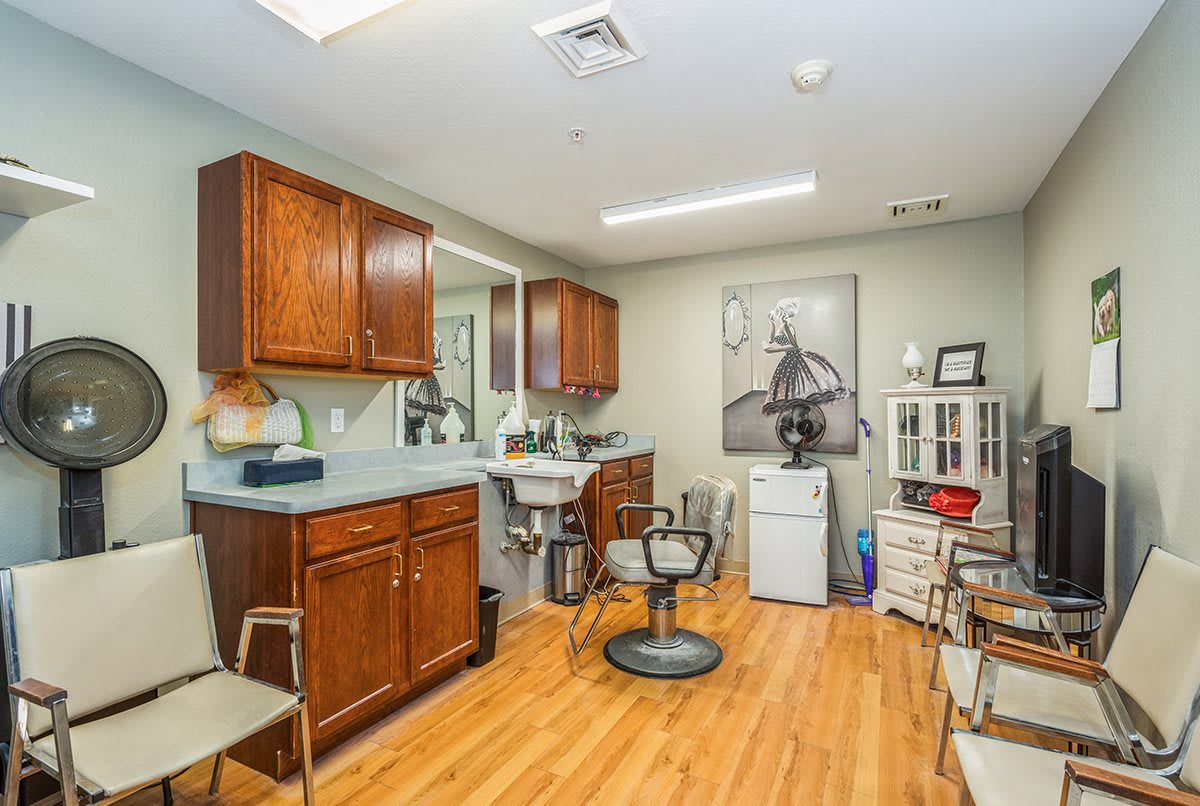 A cozy hair salon with wooden cabinets, a styling chair, and a mirror.