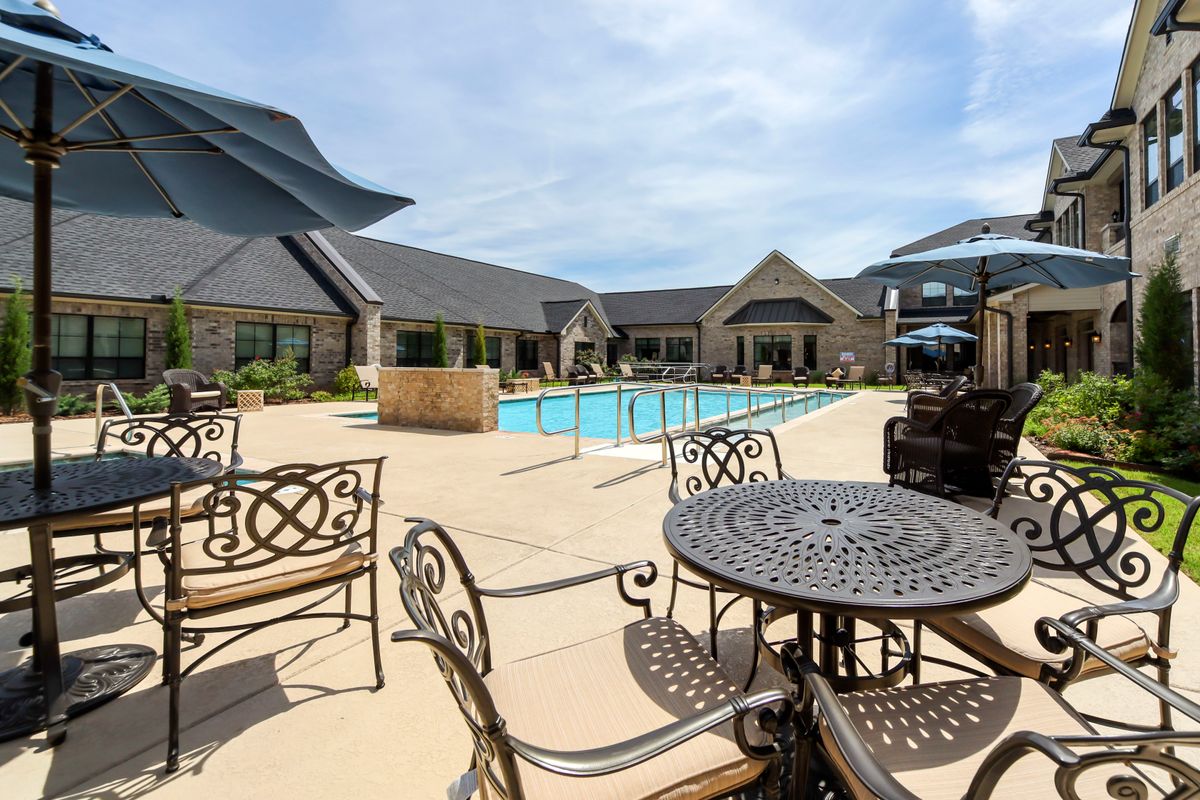A luxurious outdoor pool area with elegant patio furniture under a sunny sky.