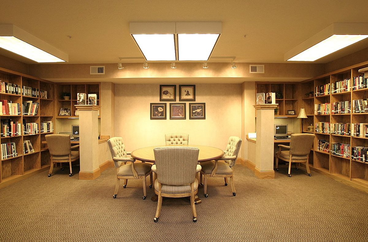 A well-organized office meeting room with a central conference table surrounded by chairs, flanked by computers on desks.