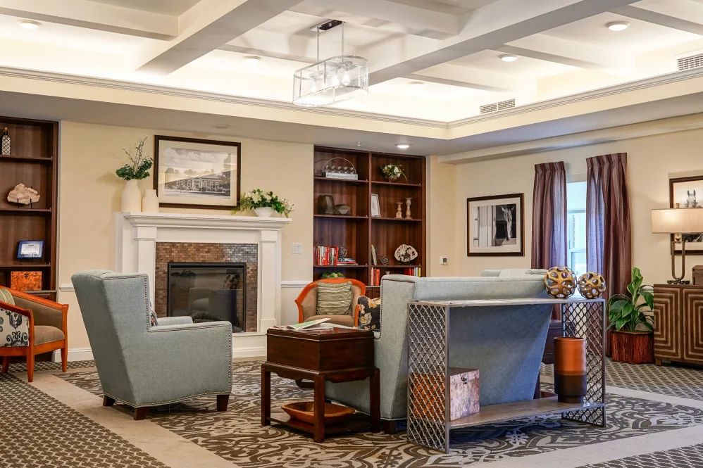 A cozy living room with elegant furniture, a fireplace, and bookshelves.