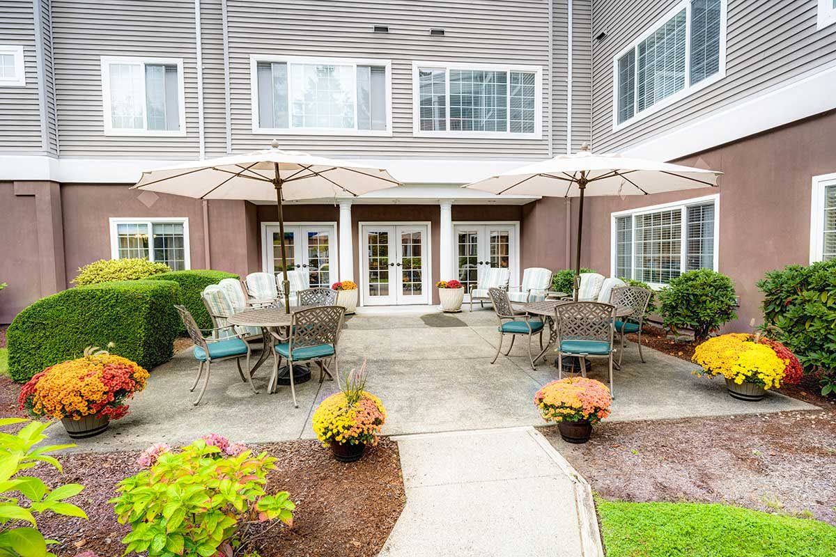 A welcoming outdoor patio area with tables, chairs, and umbrellas in a landscaped garden setting.