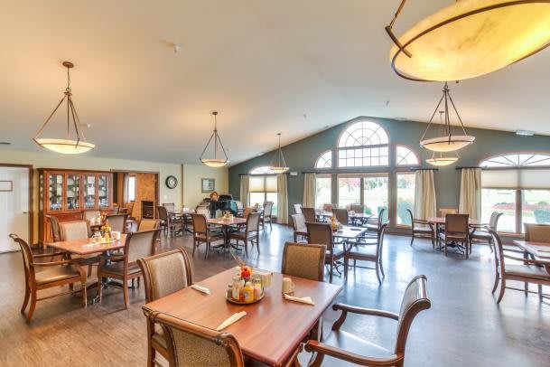 A spacious dining area with neatly arranged tables and chairs, featuring large windows and elegant lighting.