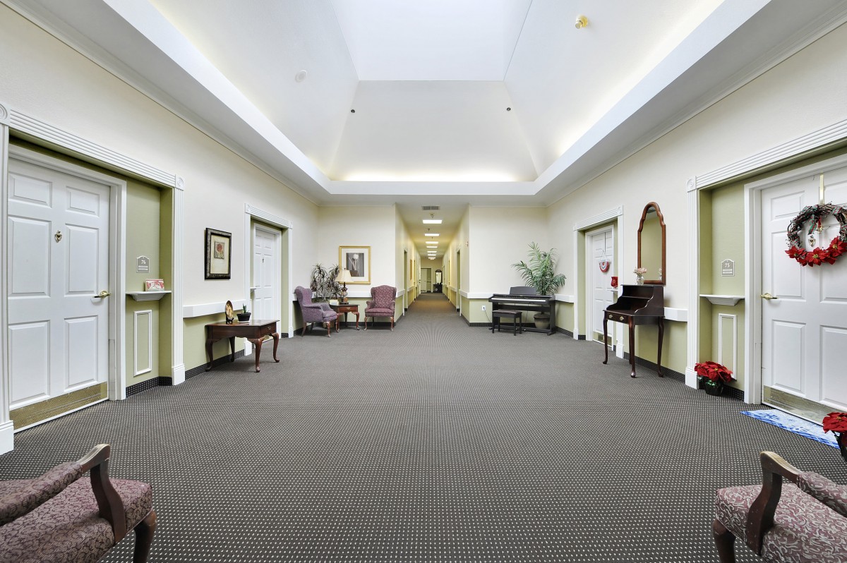 A well-lit hallway with various pieces of furniture and decorations.