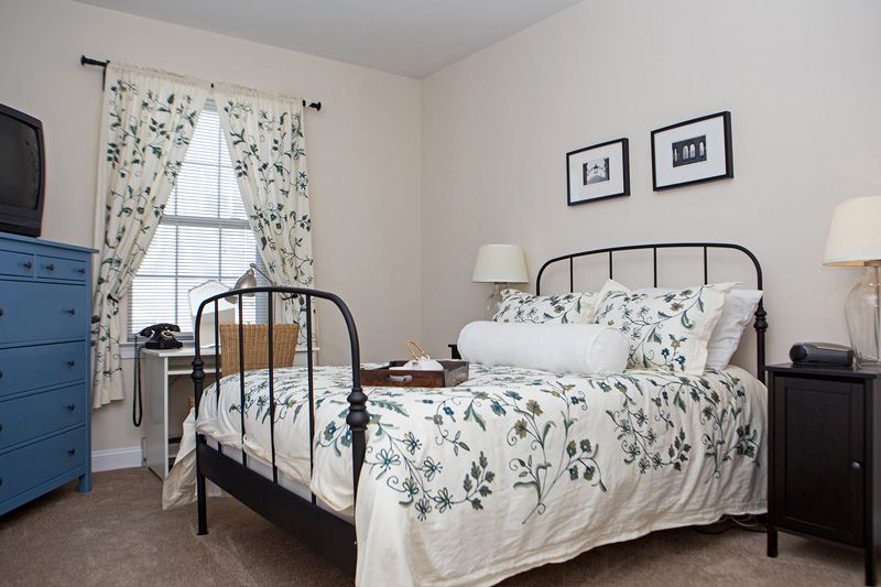A cozy bedroom with a black iron bed frame, floral bedding, and matching curtains.