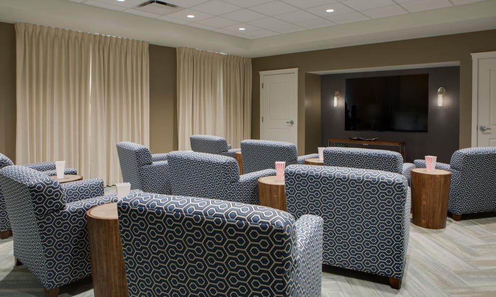 A modern conference room with patterned chairs arranged towards a large television.