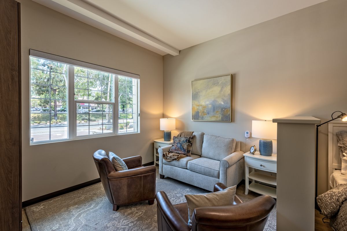A cozy living room with a sofa, two armchairs, and warm lighting.