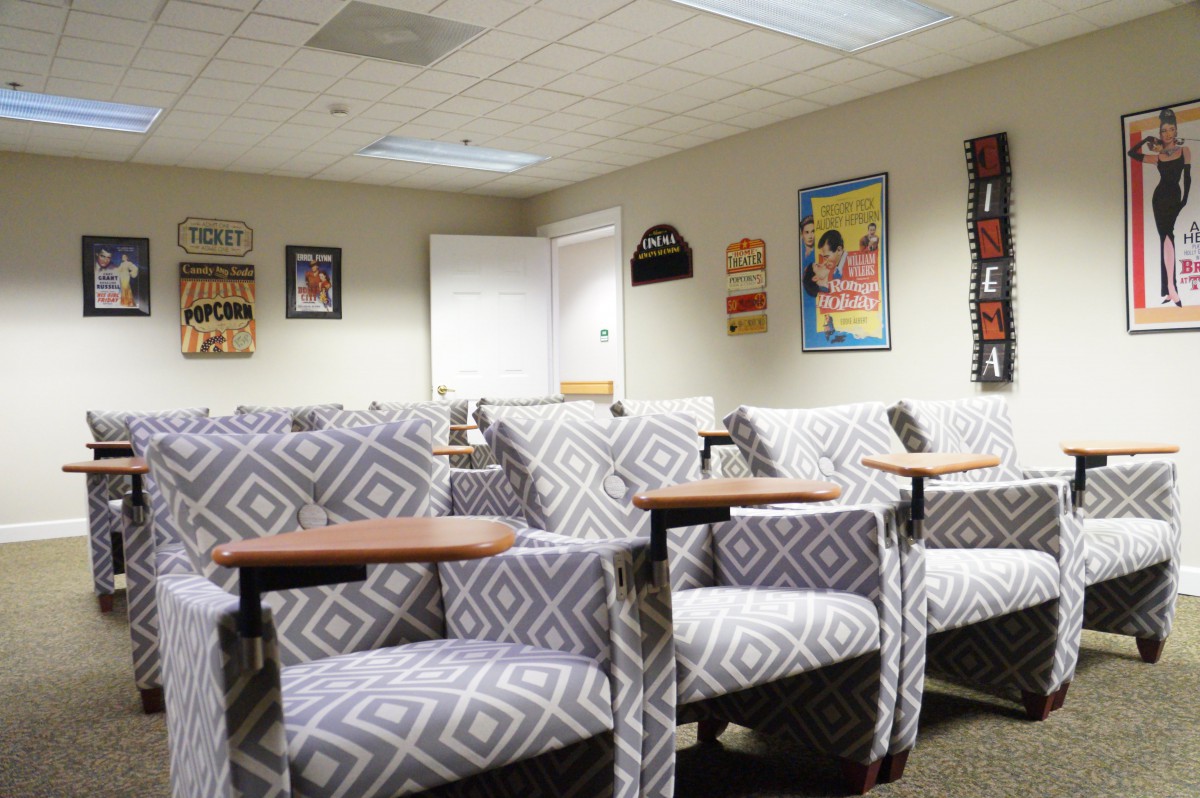 An empty waiting room with patterned chairs and colorful posters on the walls.