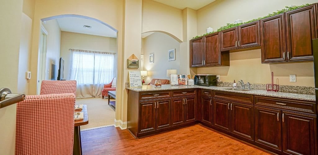 A cozy kitchen area with wooden cabinets and an adjoining bright living room.