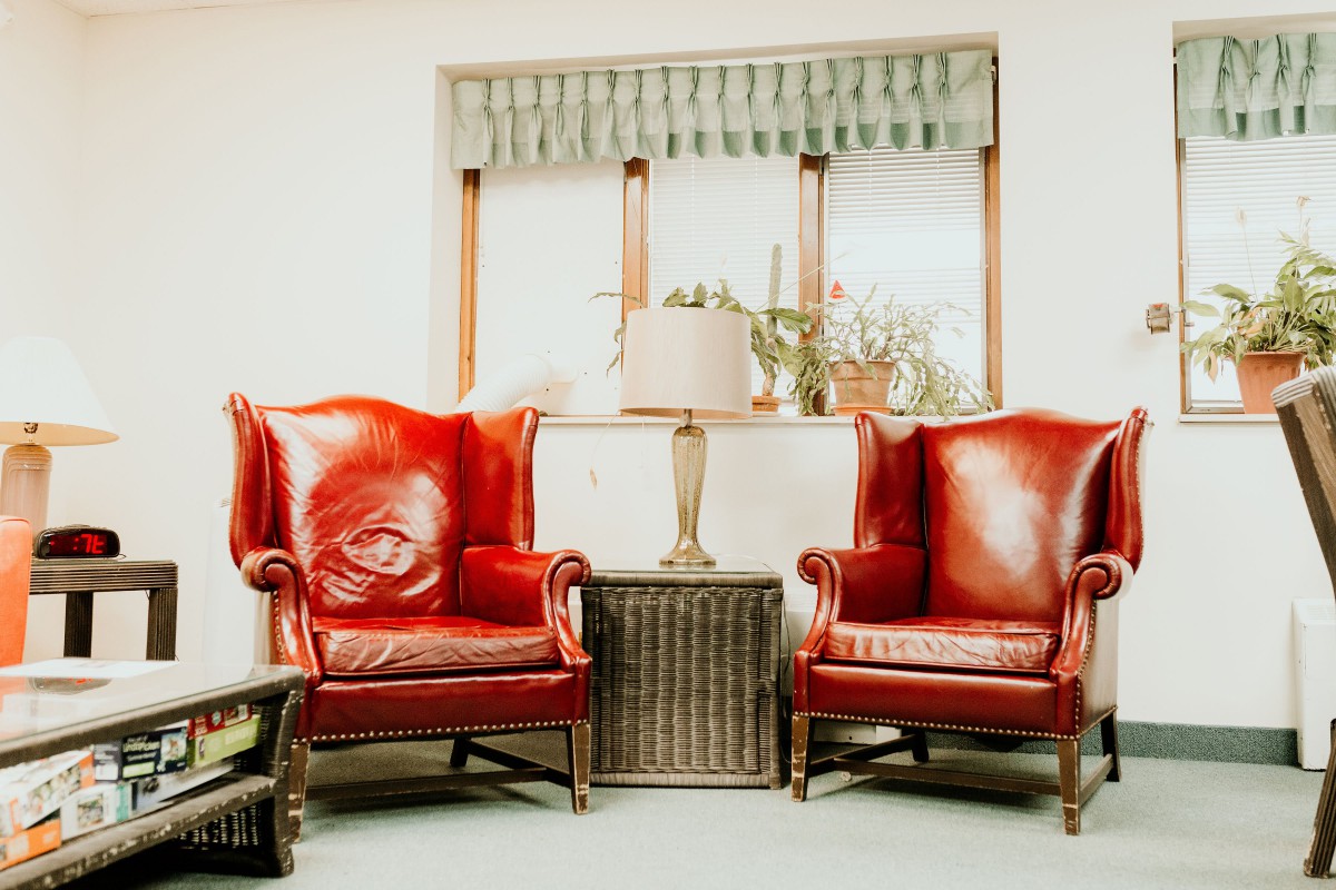 A cozy living room setup with two vintage red armchairs, a side table, and a lamp by the window.