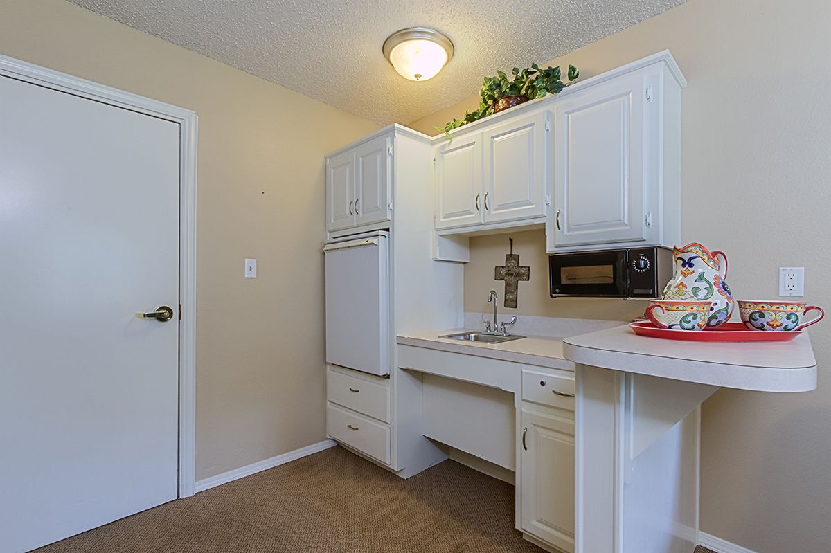A compact laundry room featuring white cabinetry and a sink.