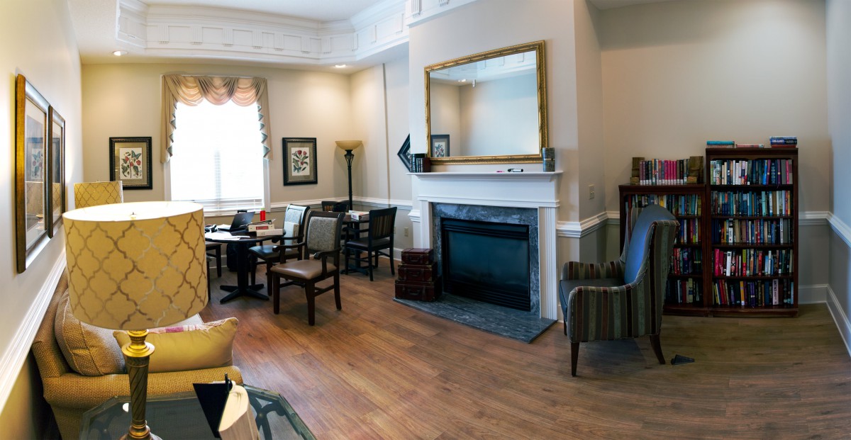 A cozy living room with a fireplace, surrounded by chairs and decor.