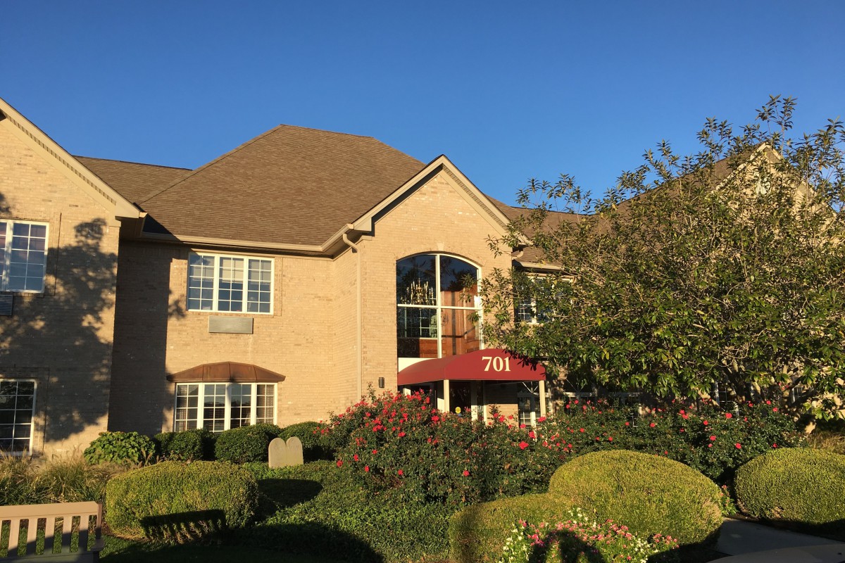 A large suburban house with a well-maintained garden on a sunny day.
