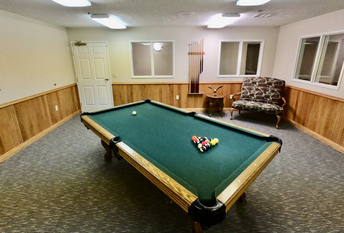 A cozy recreation room featuring a pool table and comfortable seating.