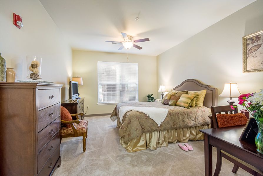 A cozy bedroom with elegant furnishings and a ceiling fan.