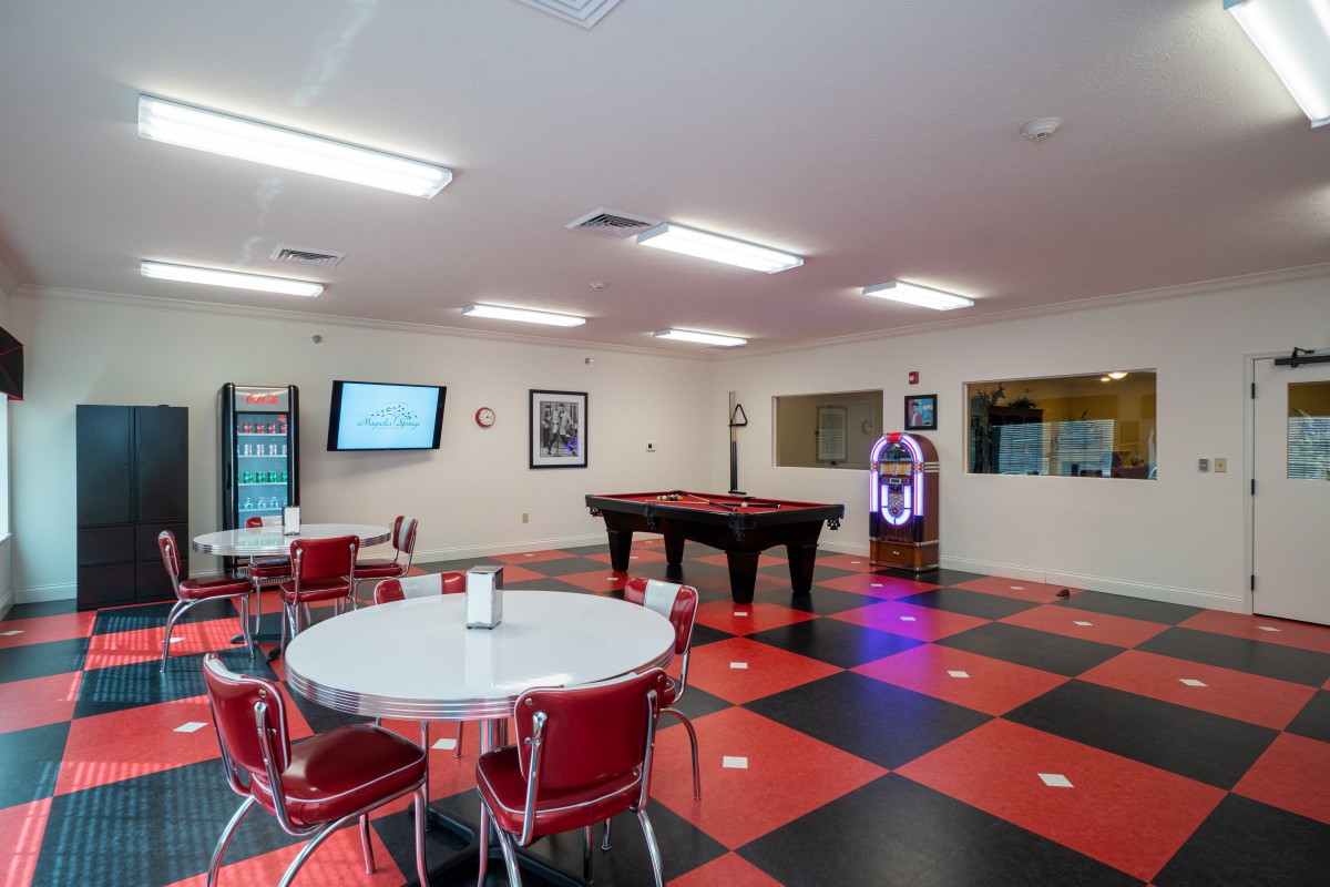 A retro-themed recreation room featuring a pool table, jukebox, and checkered flooring.