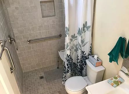 A small bathroom with a shower area and a floral shower curtain.