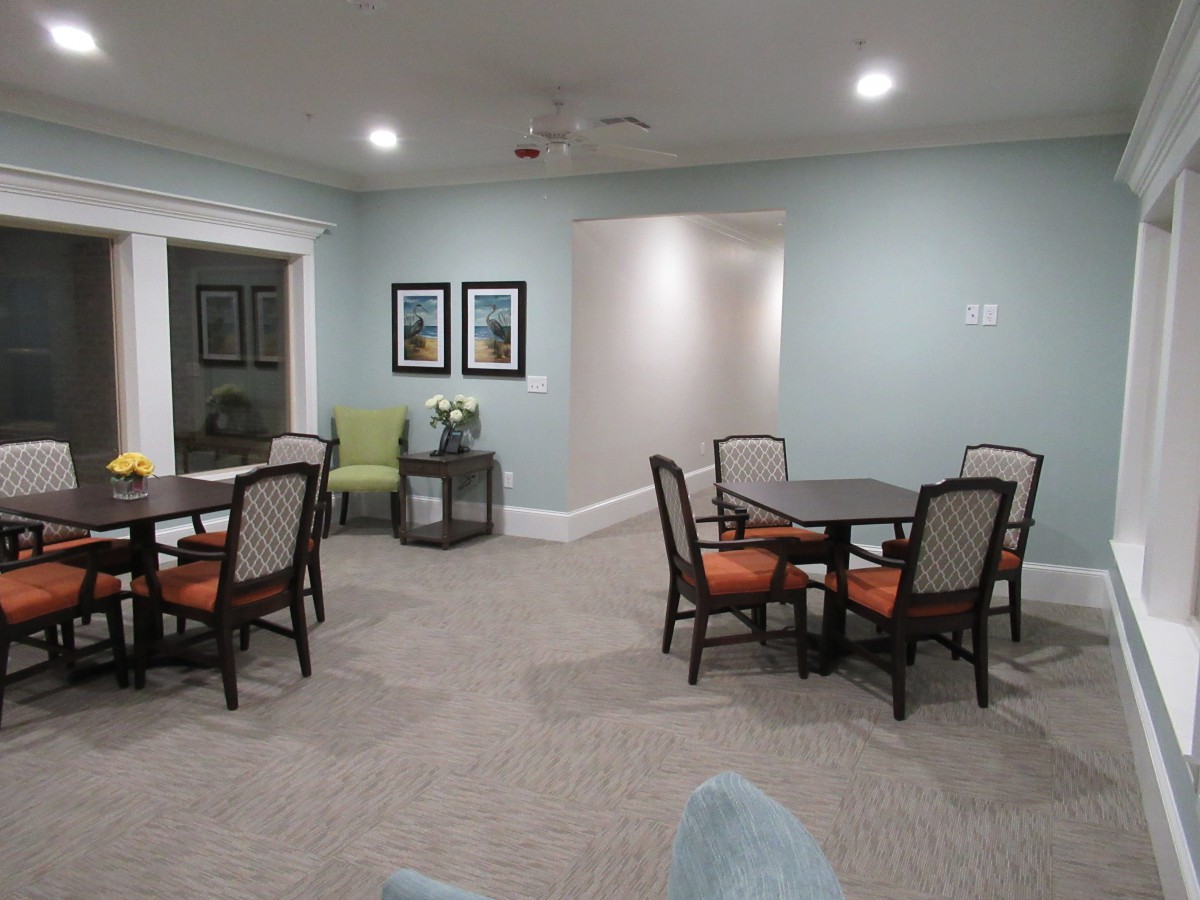 A cozy living room with tables and chairs arranged neatly on a carpeted floor.